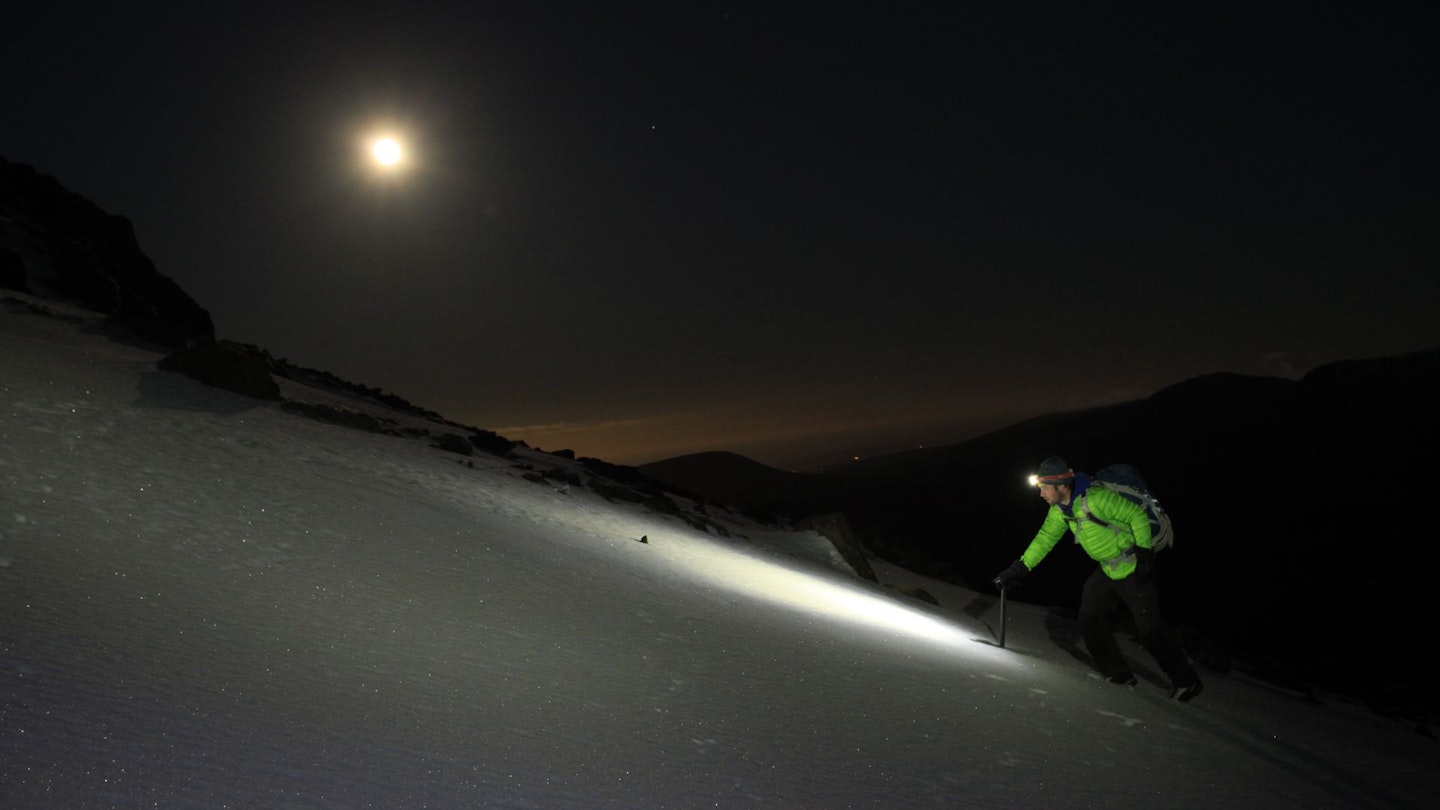 Hiker at night with full moon on Scafell Pike, Lake District