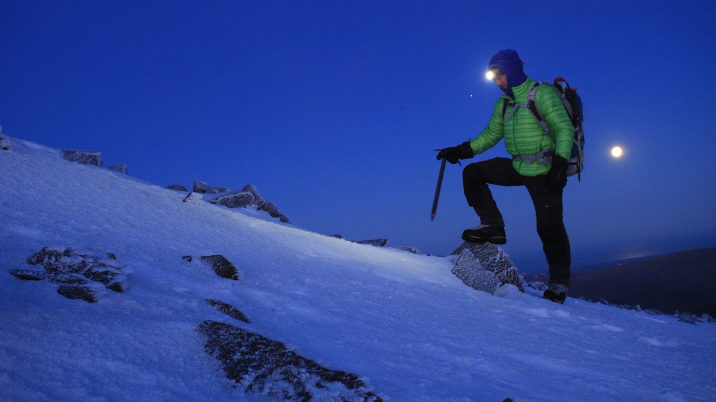 Hiker with on Scafell Pike at night with snow and full moon