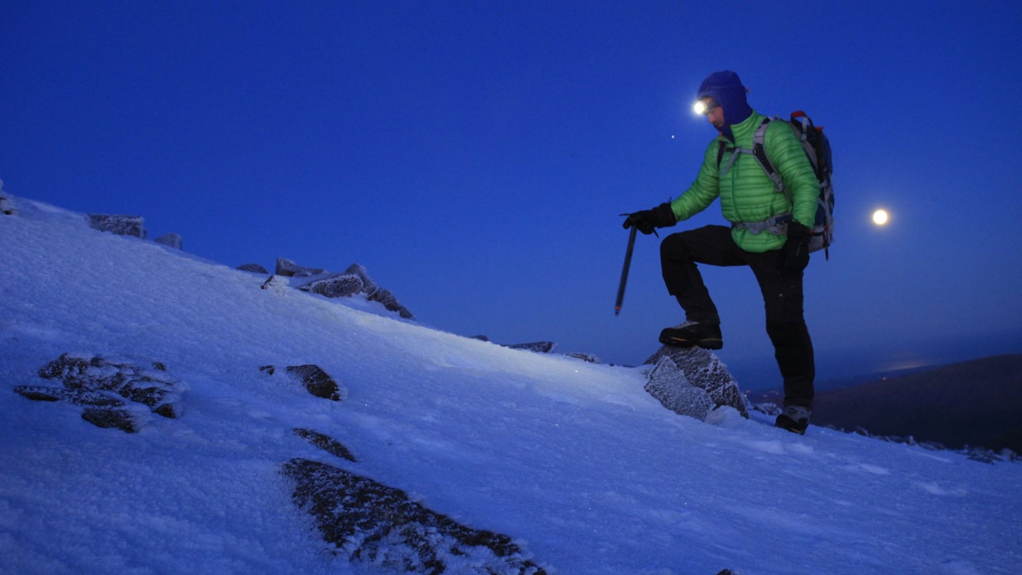 Hiker with on Scafell Pike with snow and full moon