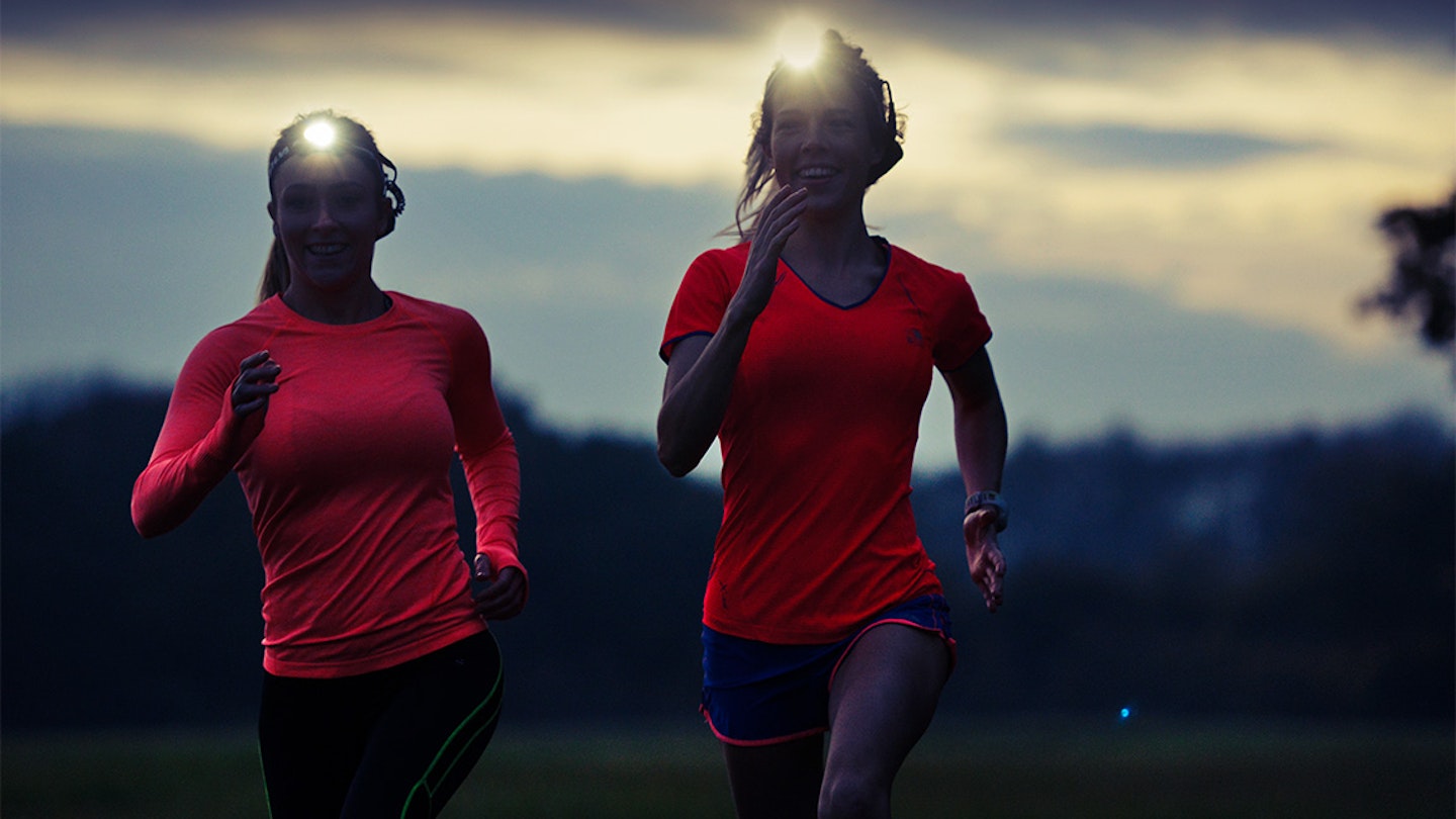 two women run in the dark with headtorches