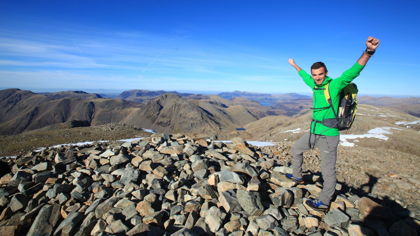 Hiker wearing walking trousers on summit of Scafell Pike