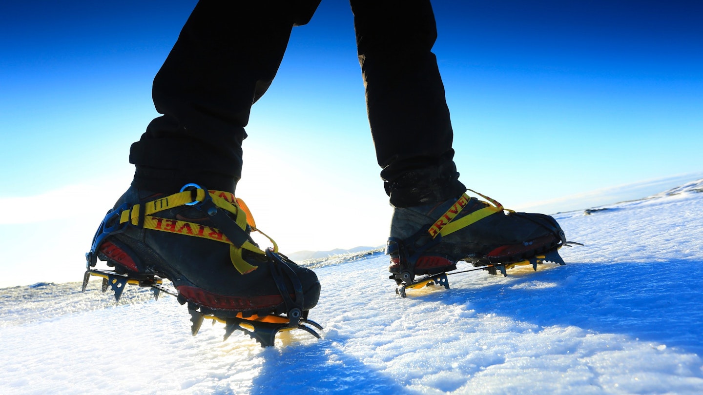Hiker wearing crampons with clear sky in background