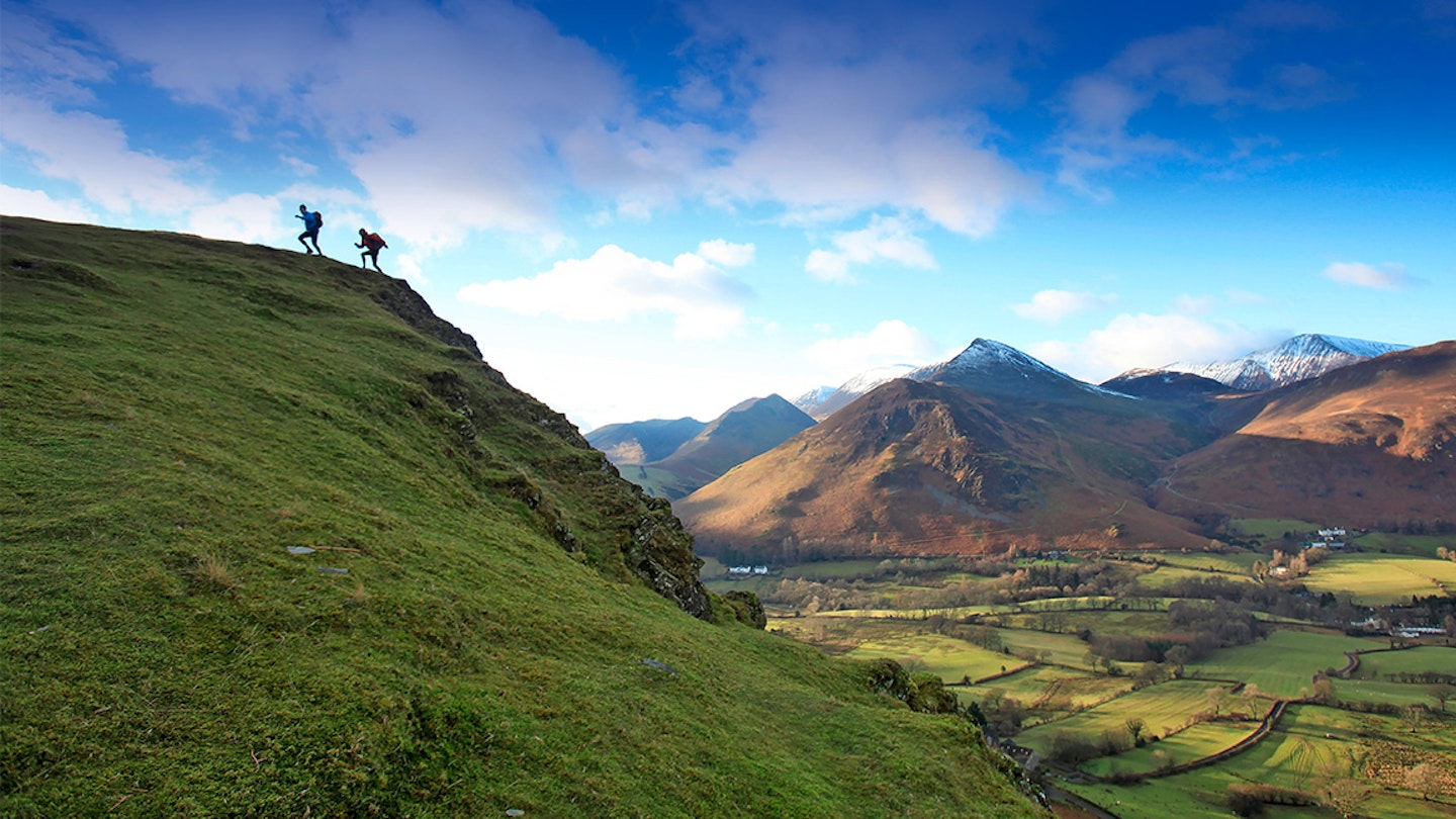 silhouette of two runners at the top of a hill