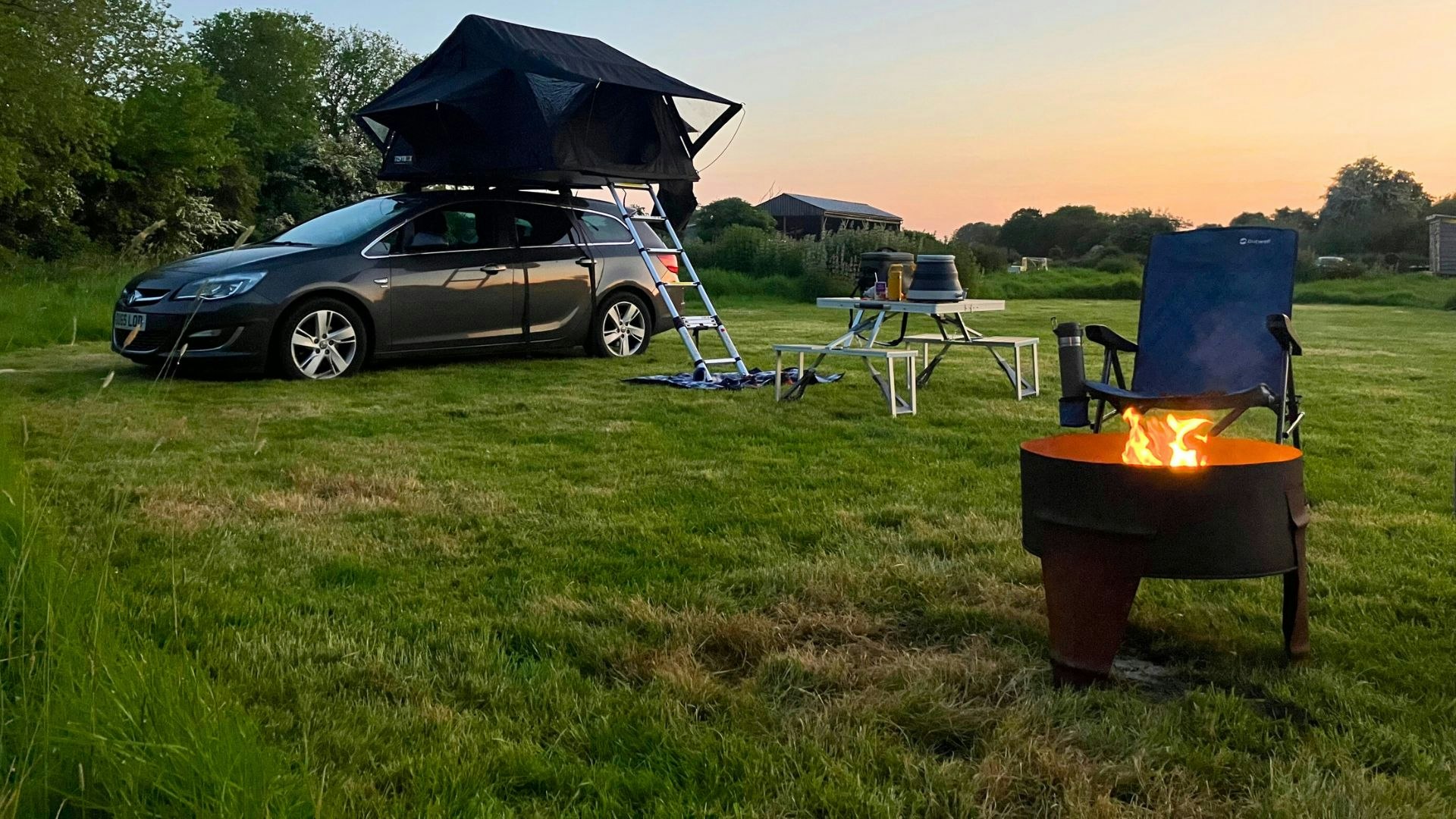 Roof tent of an estate car at a campsite at sunset