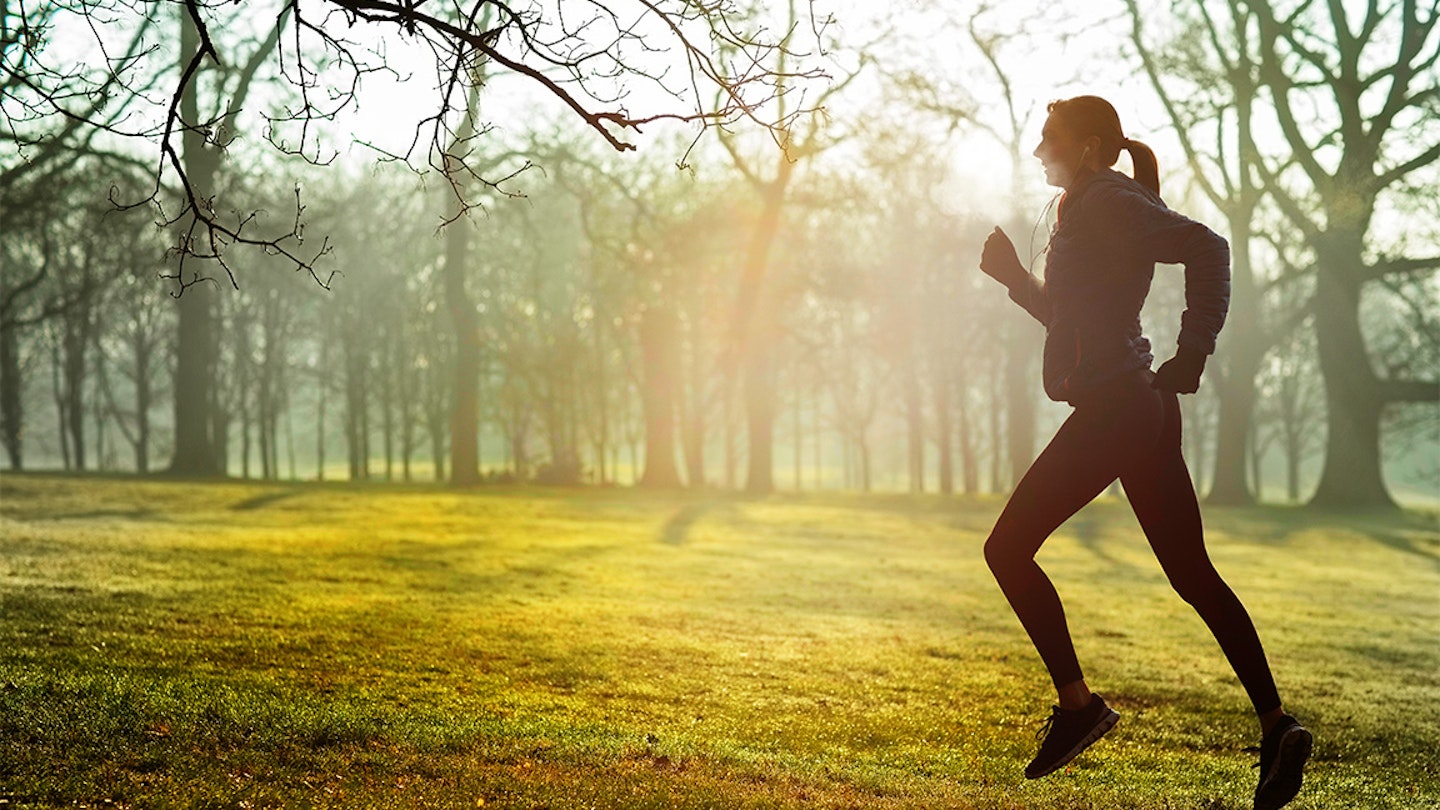 womans runs alongside some trees