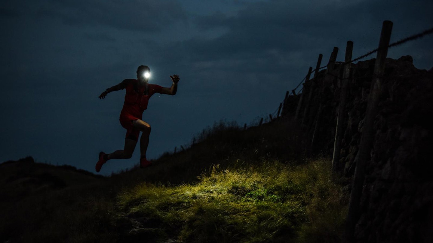 man runs through field in dark with headtorch