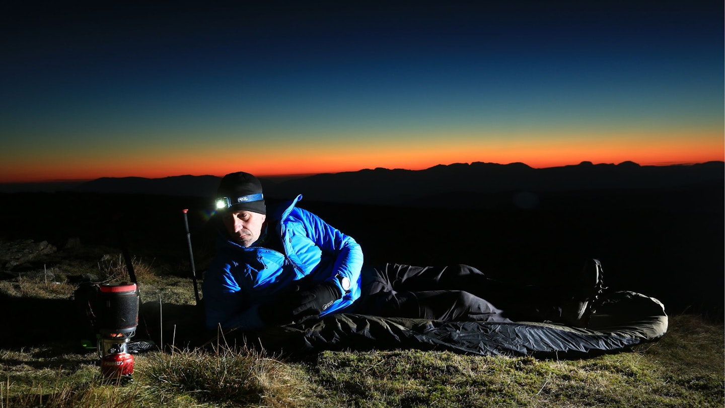 Hiker in a bivvy bag on Red Screes mountain in the English Lake District