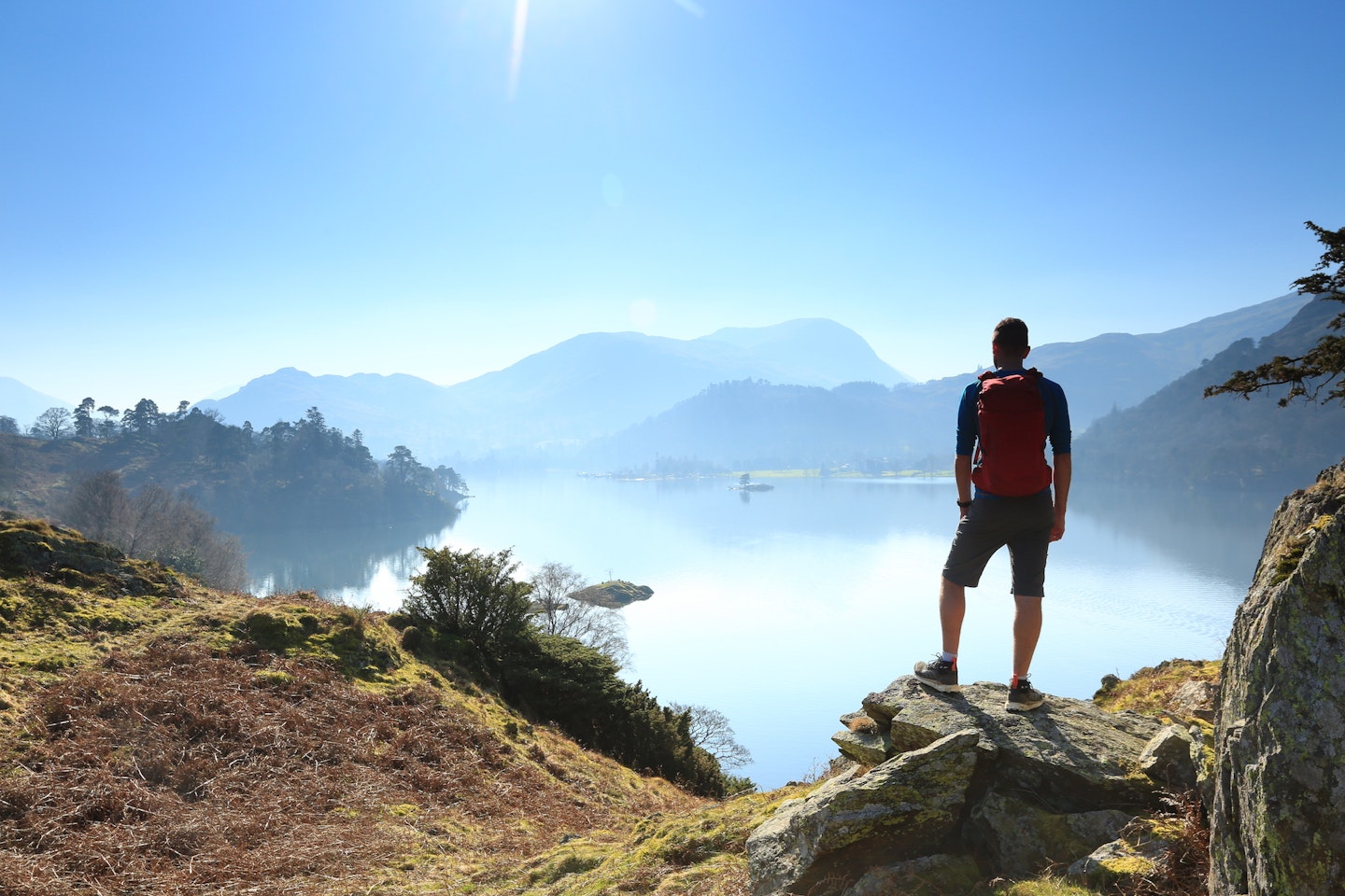 Hiker standing by a lake wearing lightweight walking boots