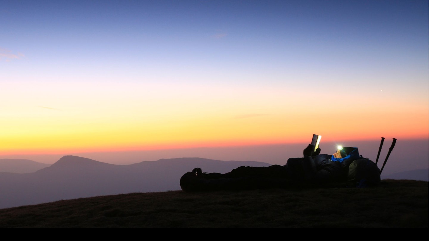 Hiker bivvying in a bivvy bag in England's Lake District mountains