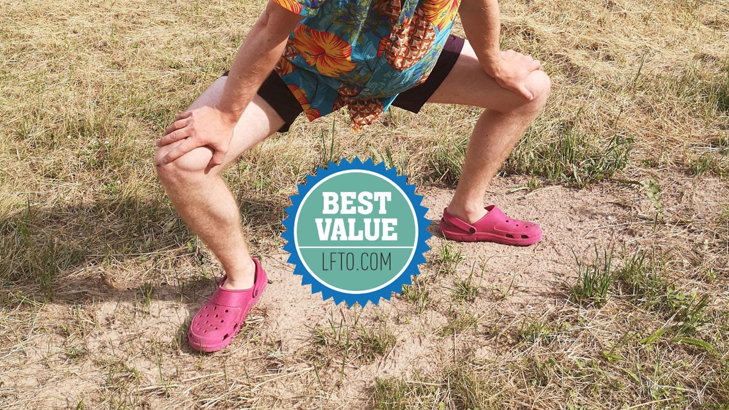 A silly man wears some crocs while squatting in a campsite