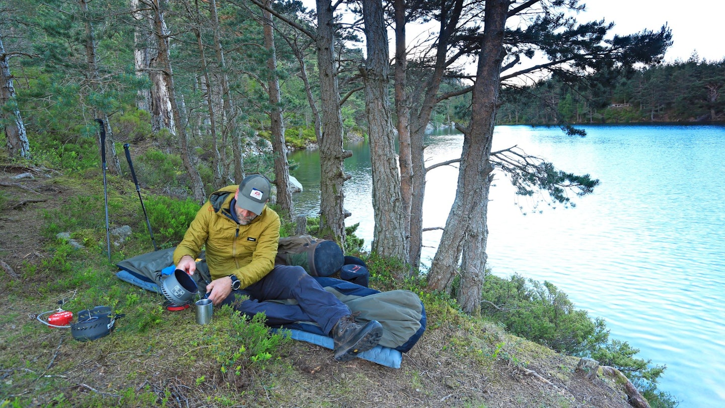 Hiker using a bivvy in a forest by a lake