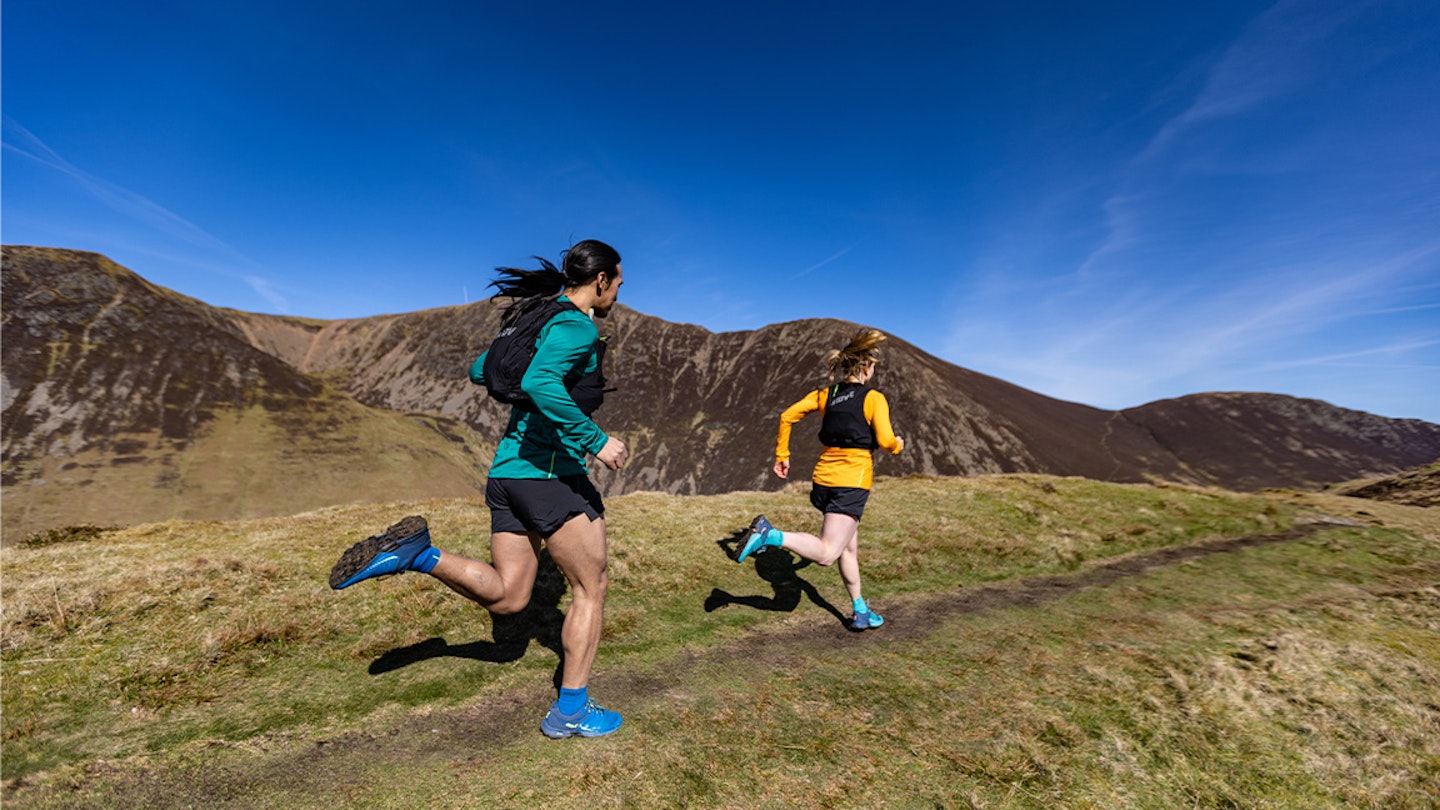 two runners run along a scree path