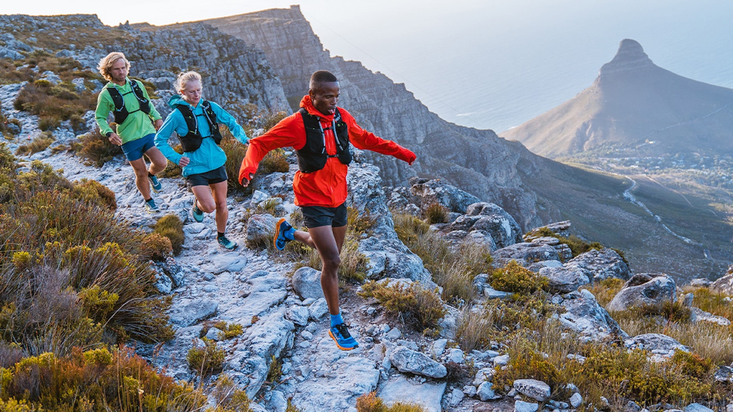 three runners run along a rocky ridge