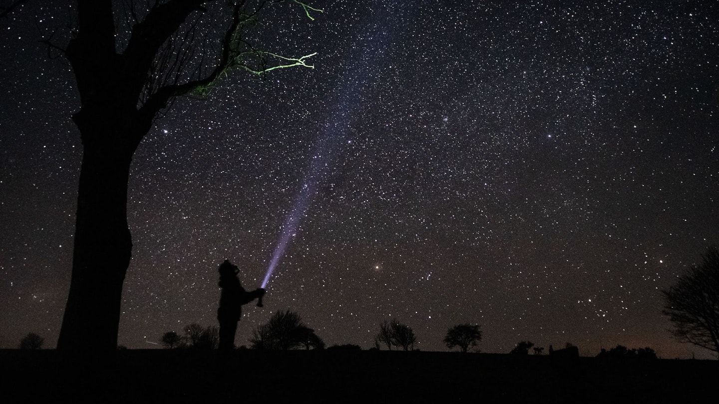 Silhouette of a person with a torch at night