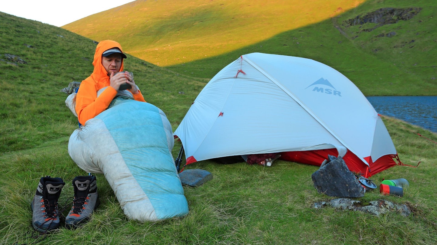 Hiker staying warm by wearing a jacket and sleeping bag