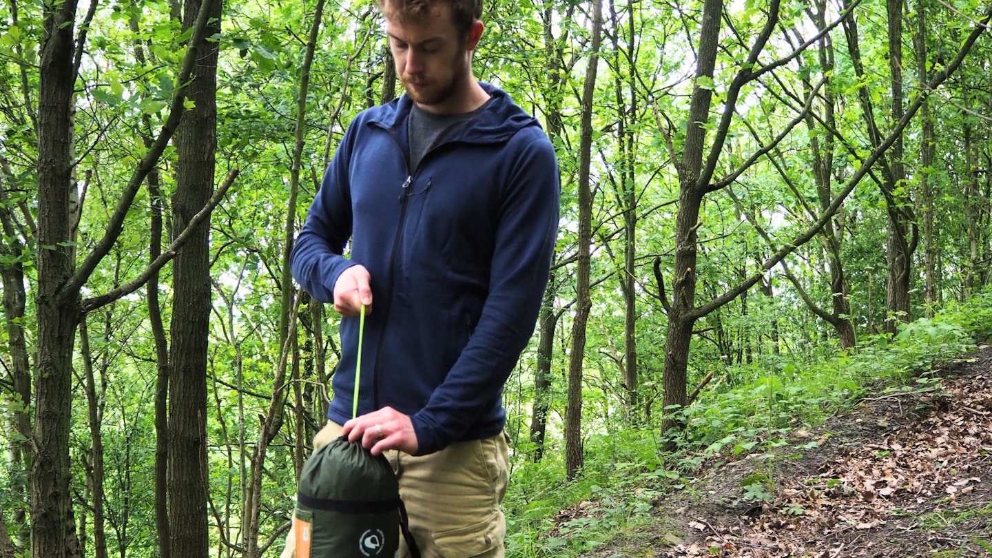 Hiker packing away a tent wearing Artilect Quandary Peak Hoodie