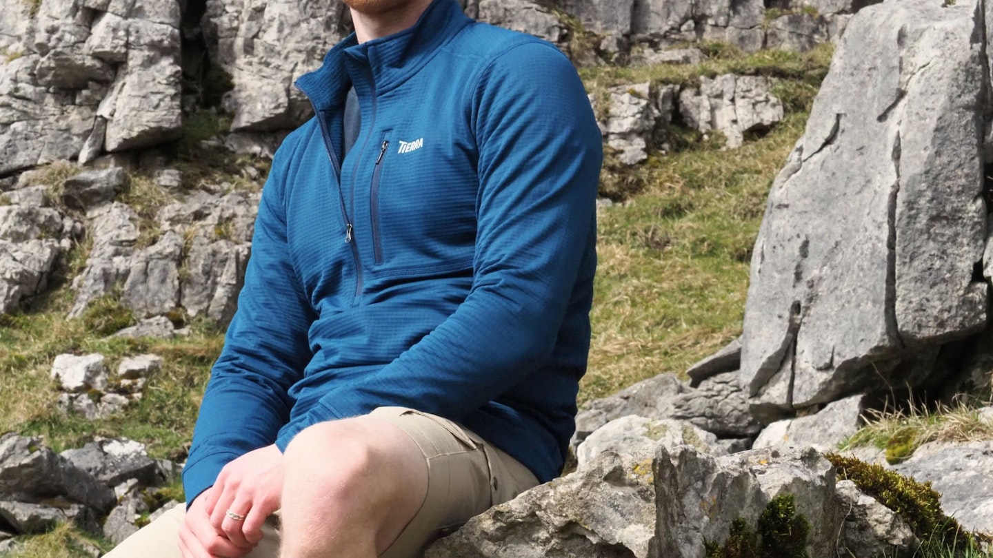 Hiker sitting on a rock wearing Tierra Nallo Half Zip