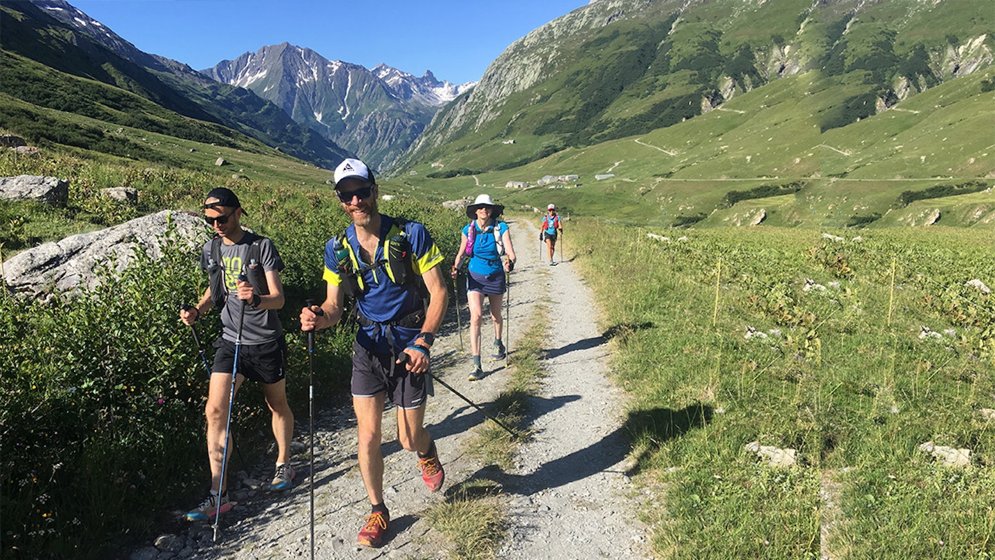 group runs with poles in the alps doing alpine trail running