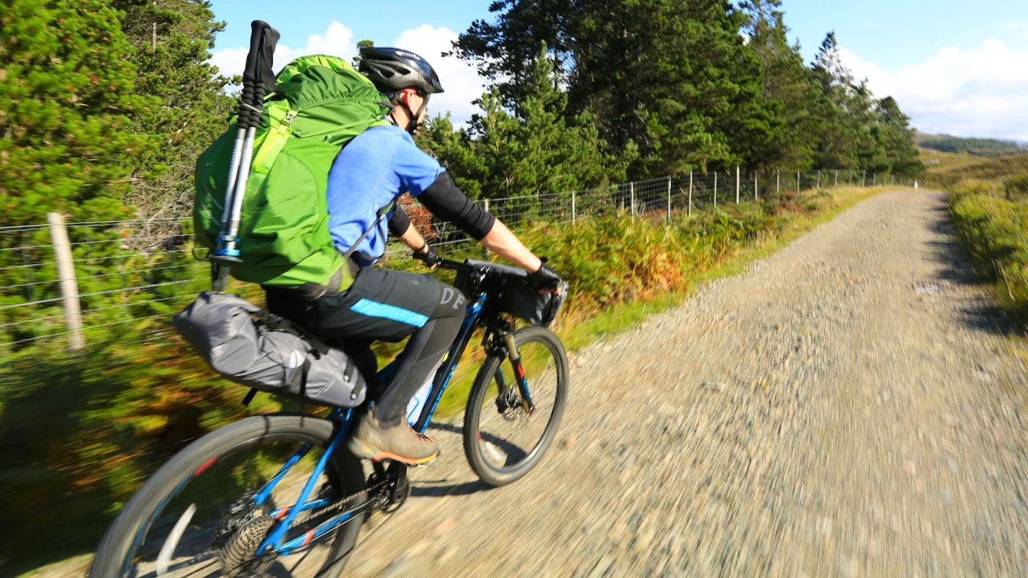 Cyclist riding a gravel track while bikepacking in Scotland