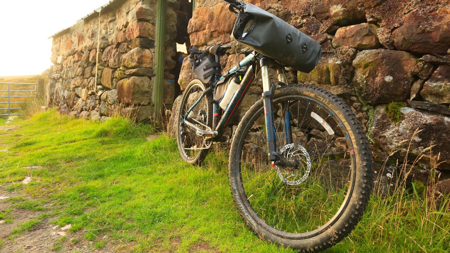 Mountain bike with bikepacking bags leaning against a bothy