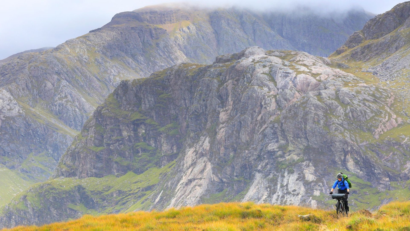 Cycling along an off-road track with Highland mountains in the background