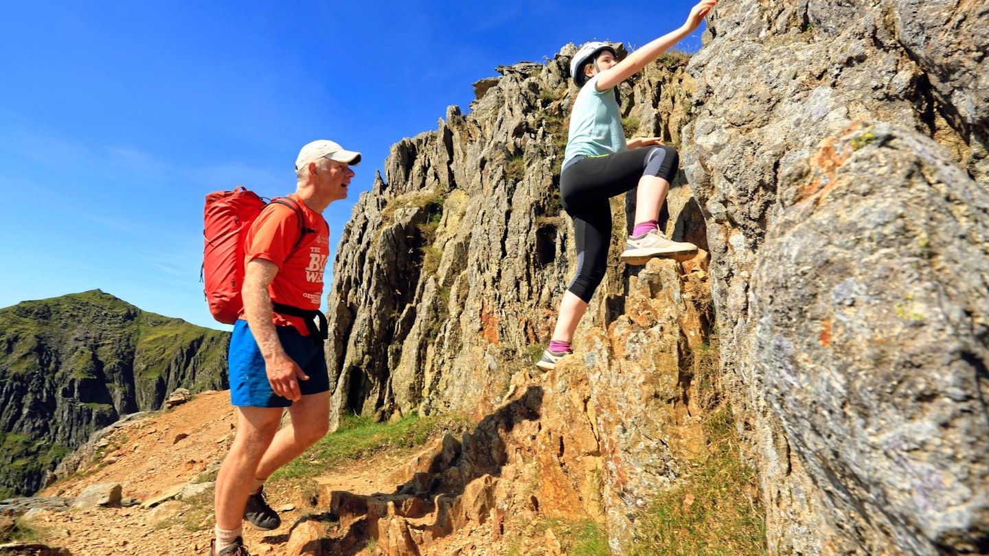 Hiker scrambling with their child on Crib Goch