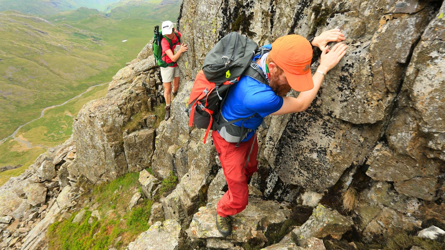 Hikers scrambling up a rock face