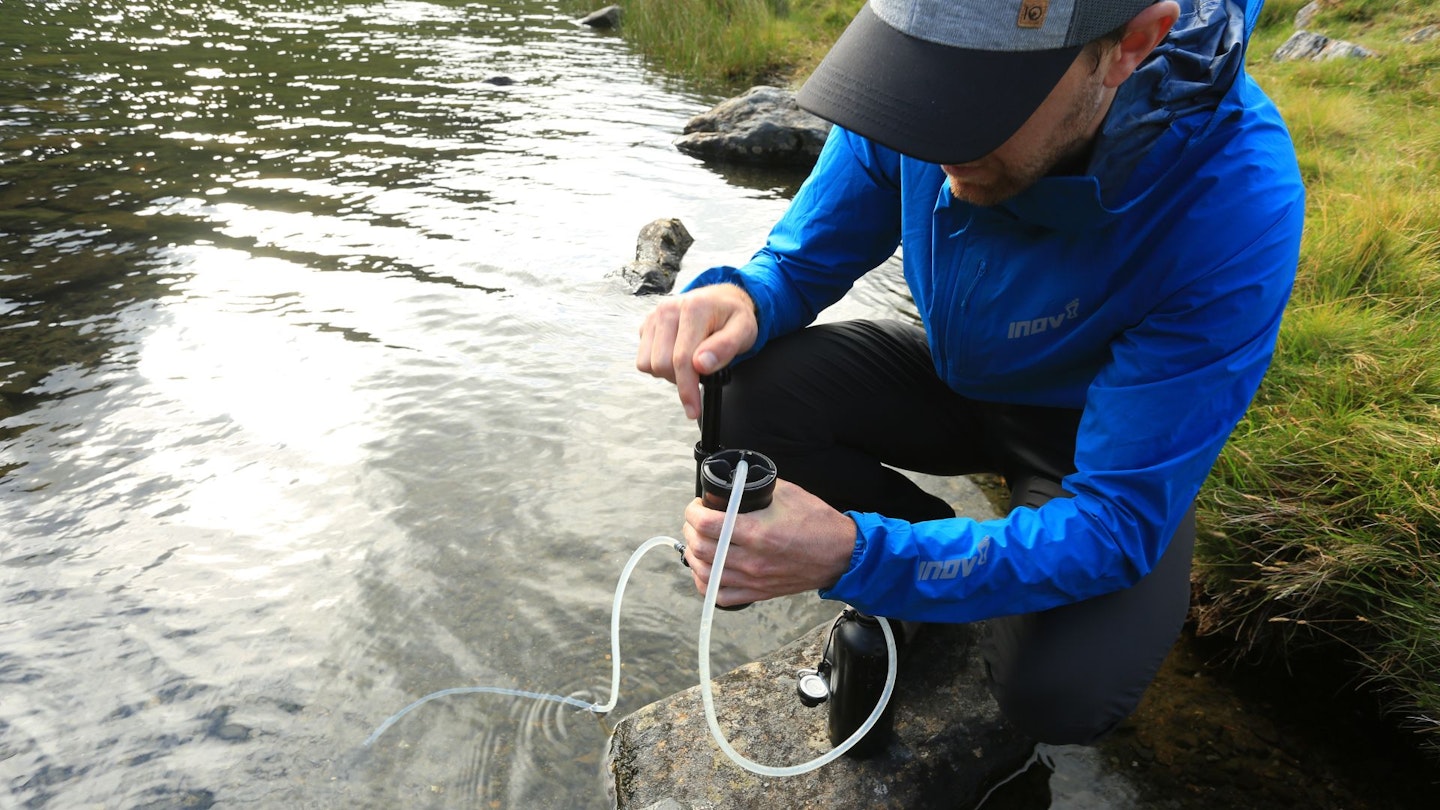 Our ultralight backpacker using a water filter at a stream