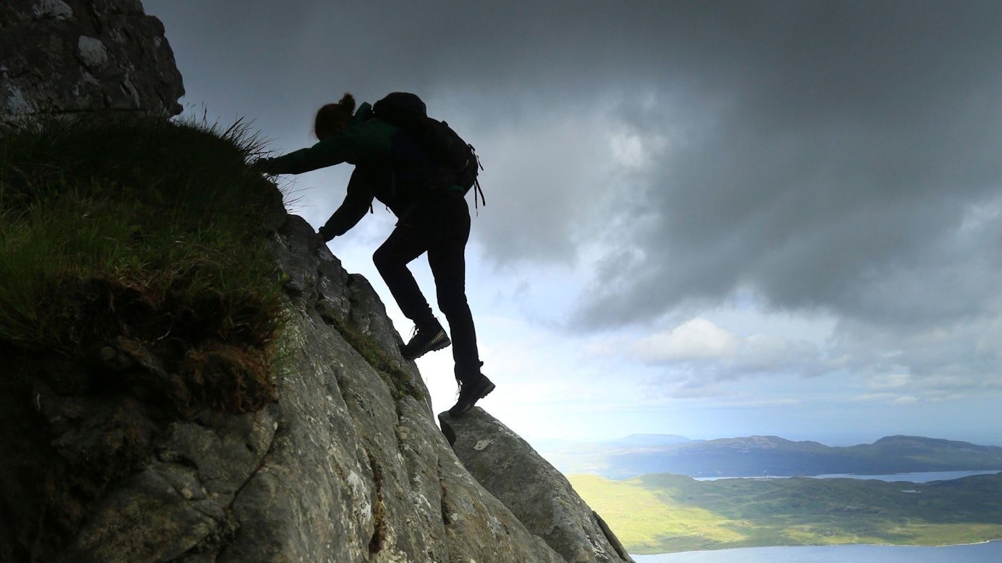 Hiker scrambling on Ben Hope, wearing approach shoes