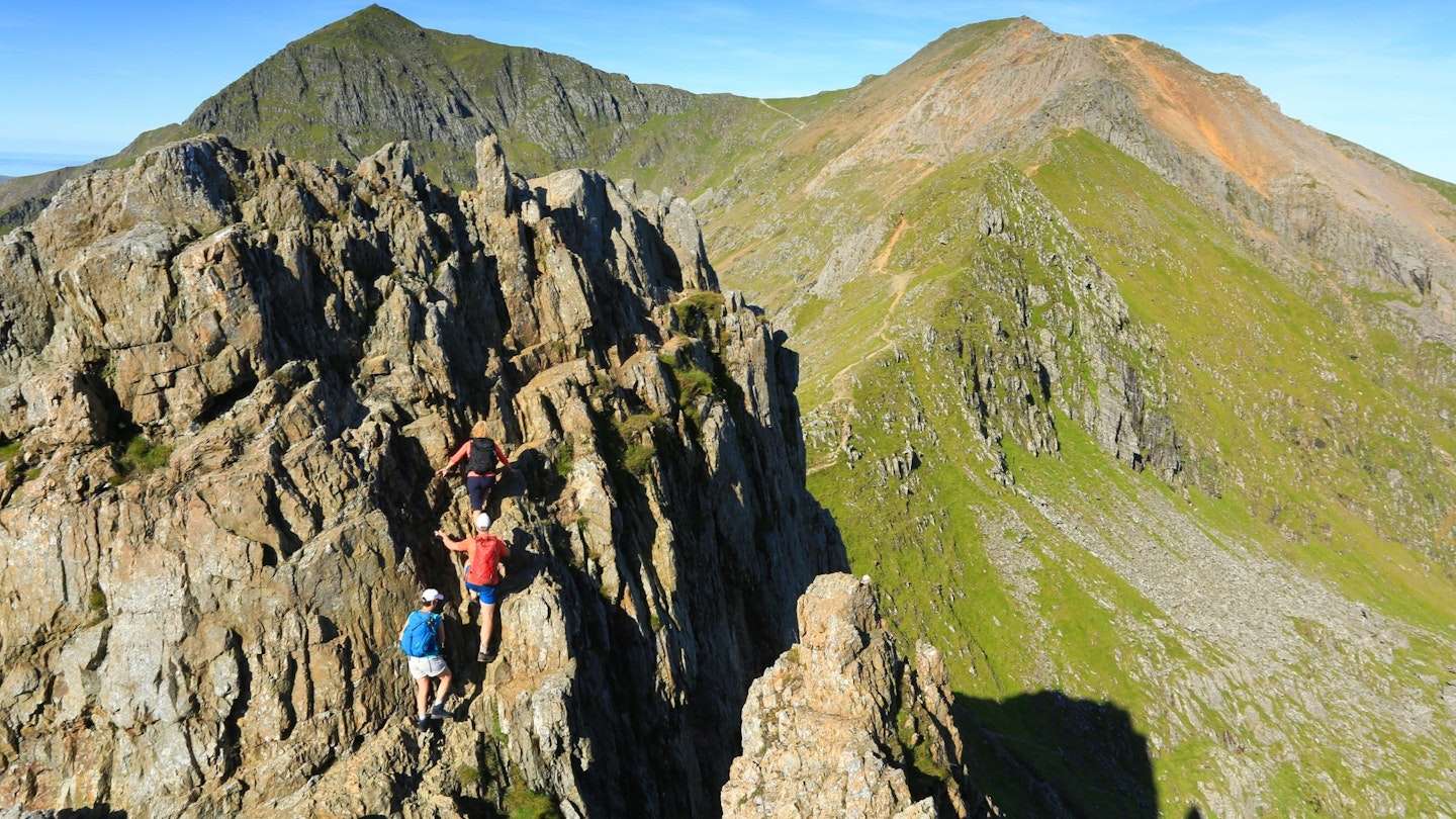 Hikers scrambling up a tower on Crib Goch, using approach shoes