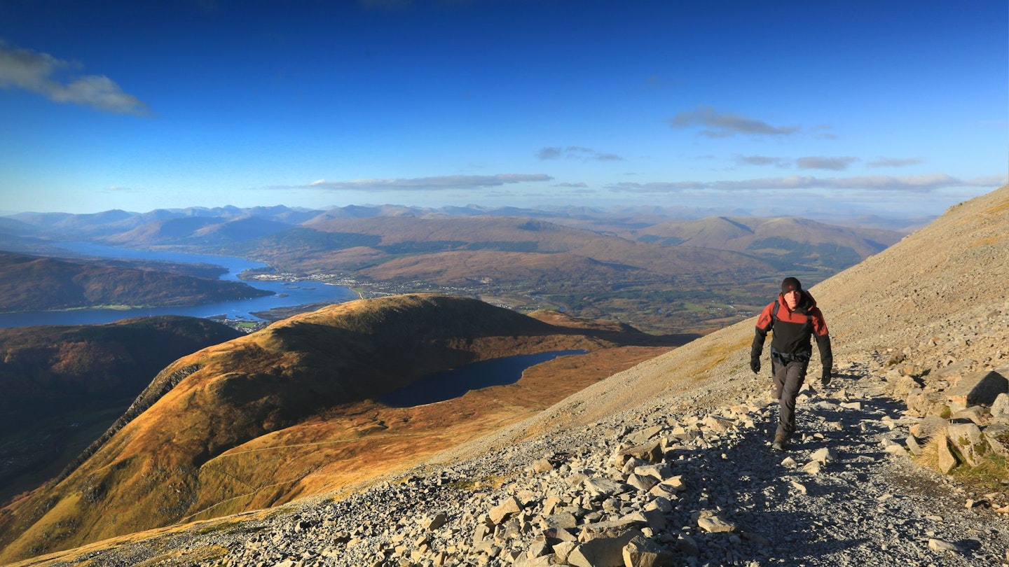 Walker climbing up the Ben Nevis Mountain Track from the halfway lochan