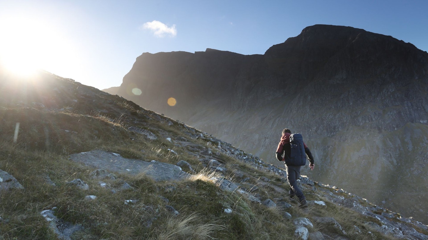 Walker climbing Carn Mor Dearg with the Ben Nevis North Face beyond