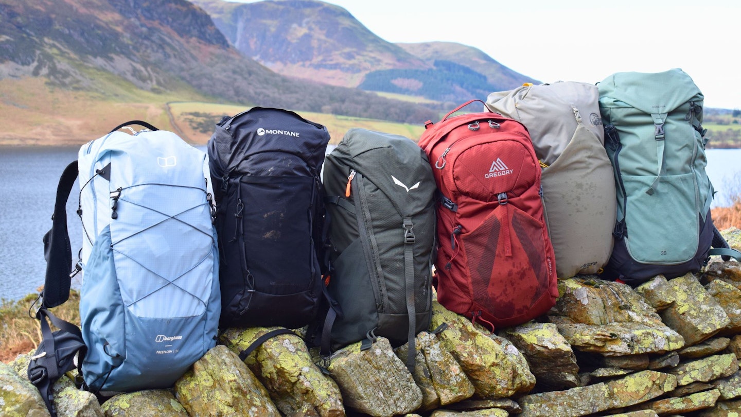 6 hiking daypacks sitting on a wall