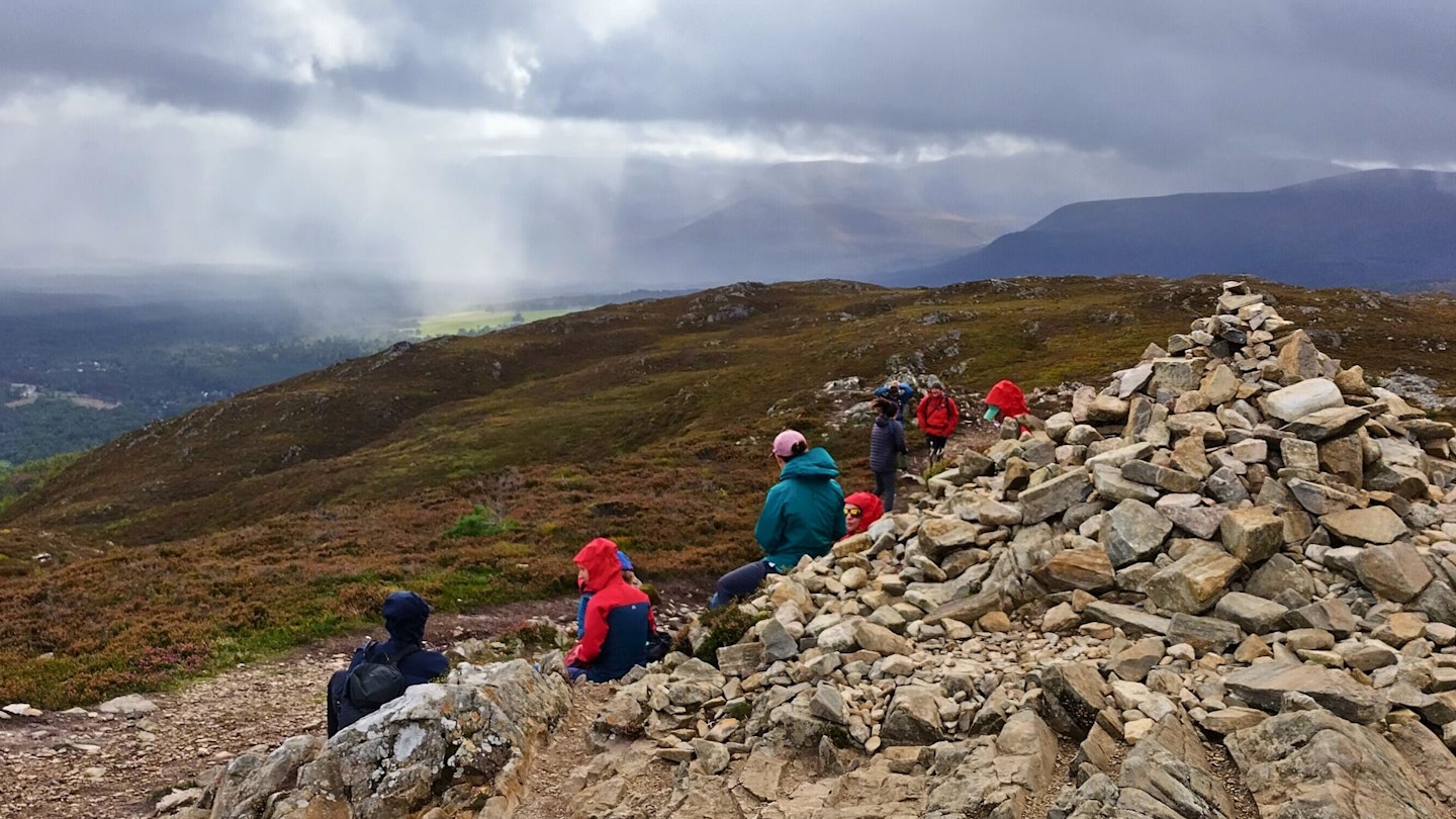 Group of hikers wearing Gore-Tex ePE jackets resting by a cairn