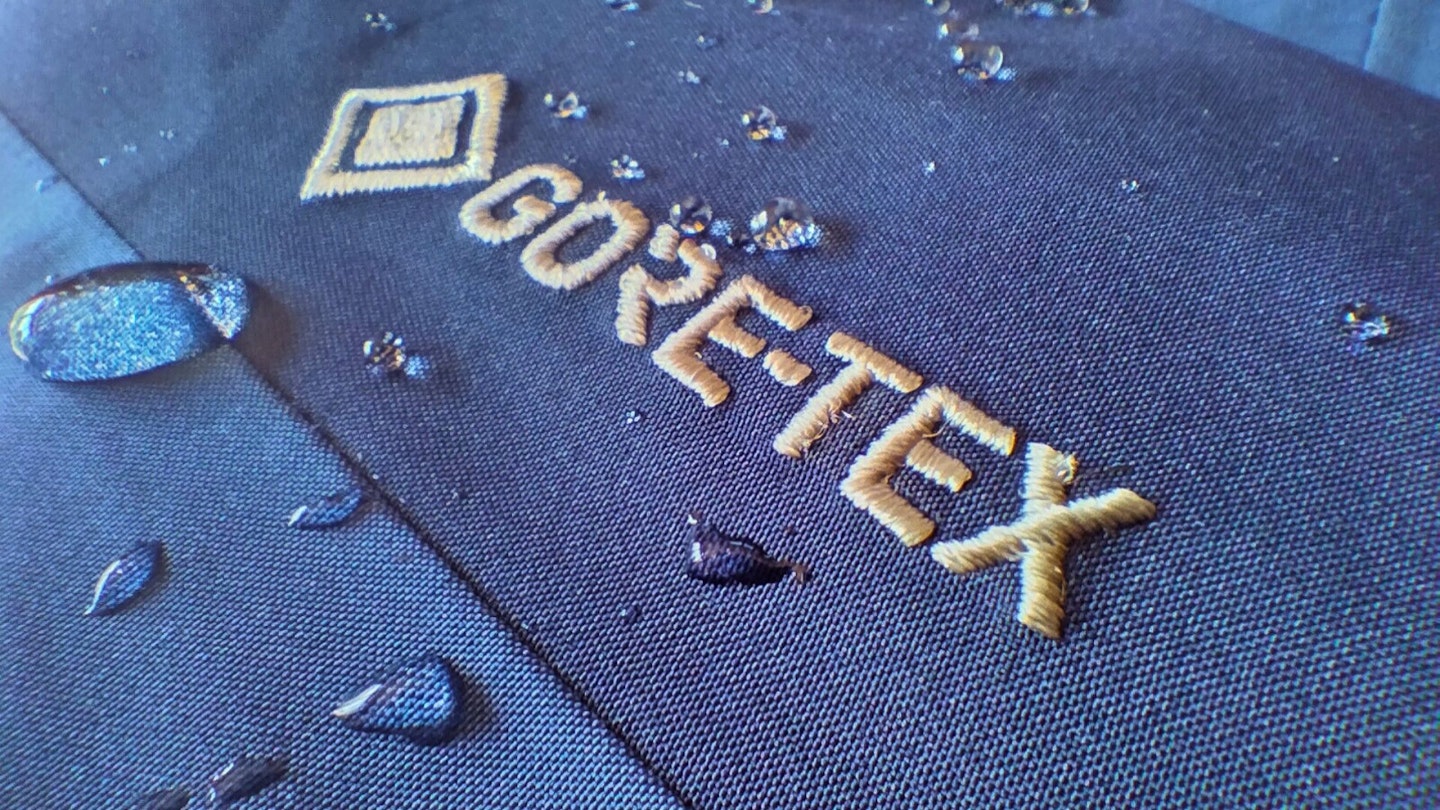 Macro shot of Gore-Tex logo stitched into a jacket with water droplets around it