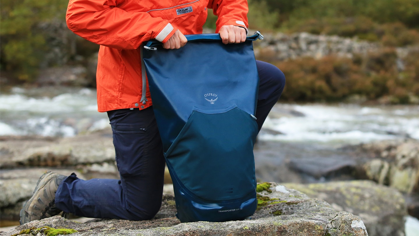 Rolling down the rolltop closure on the Osprey Transporter waterproof backpack