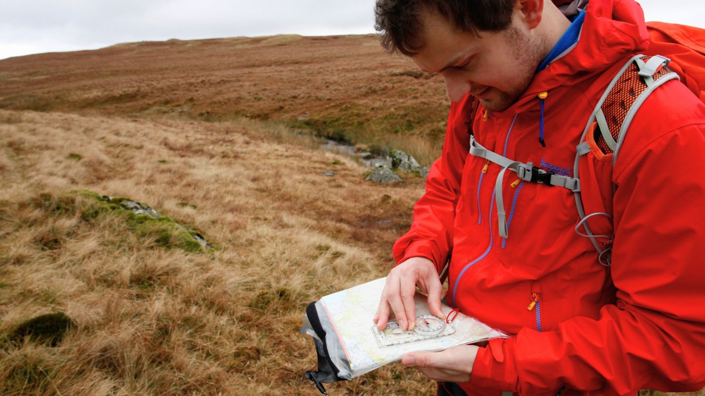 Hiker navigating with a map and compas