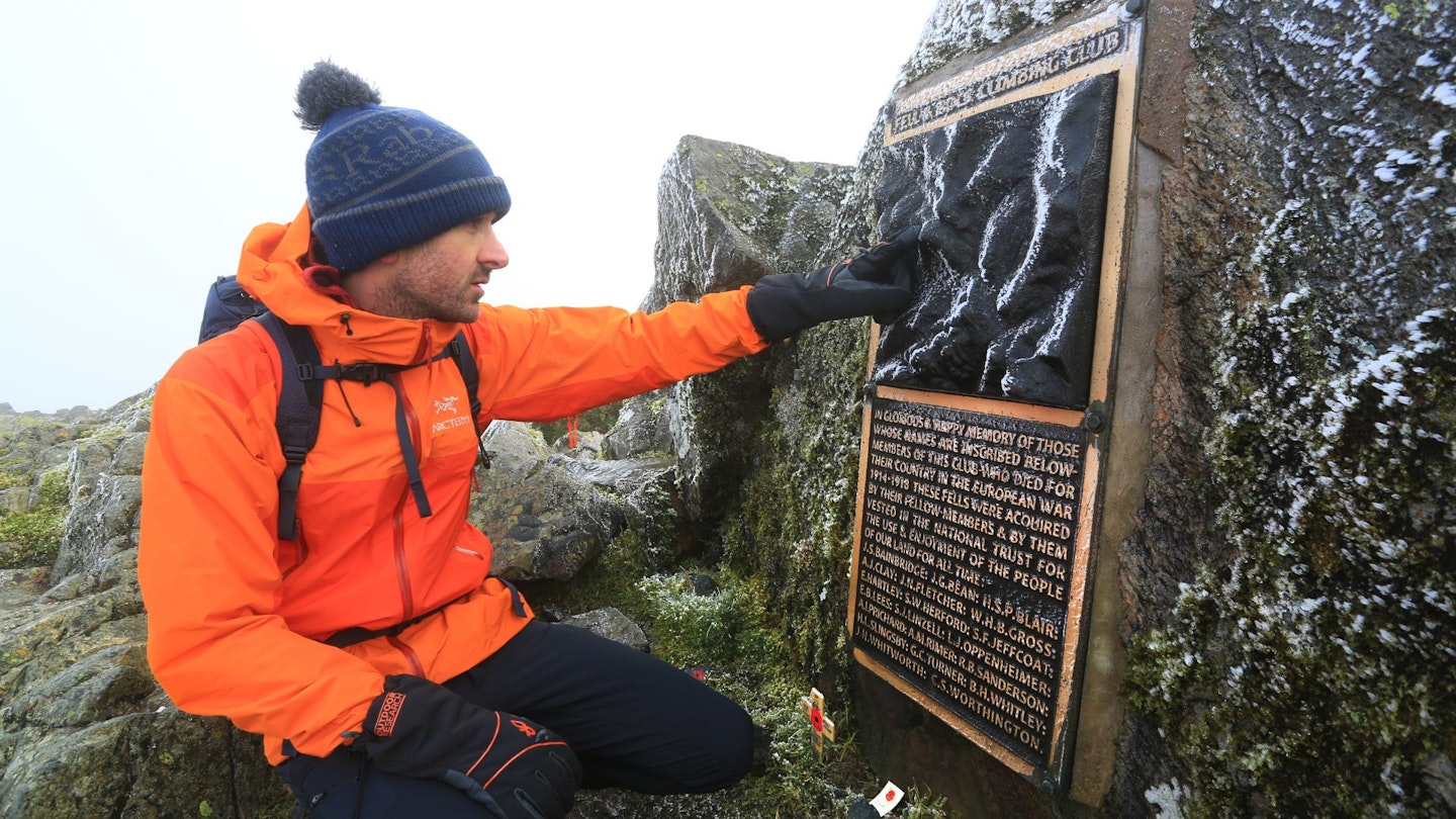 Walker at the Great Gable summit memorial in the Lake District
