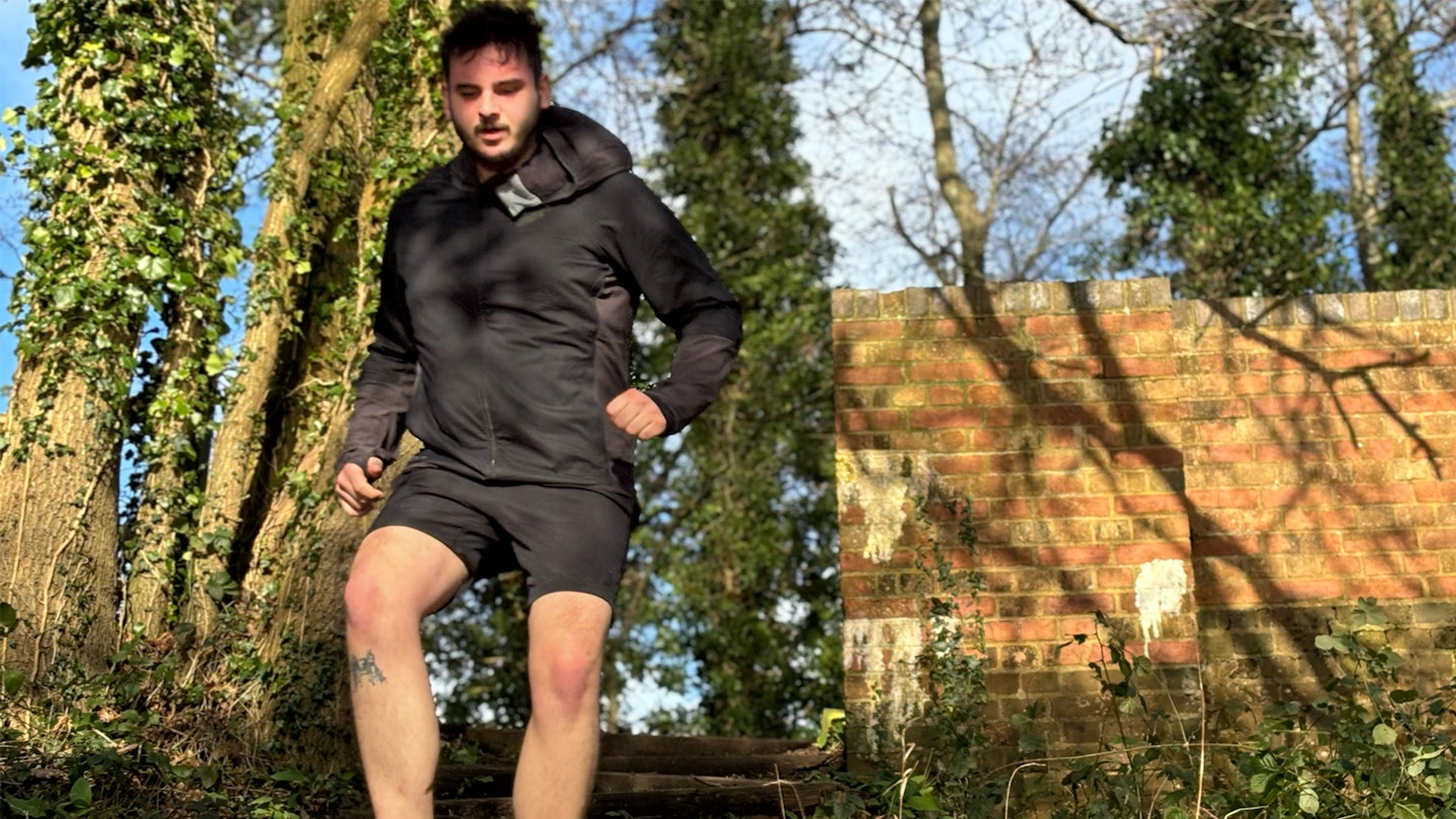 trail runner wearing black shorts and the inov8 performance hybrid jacket