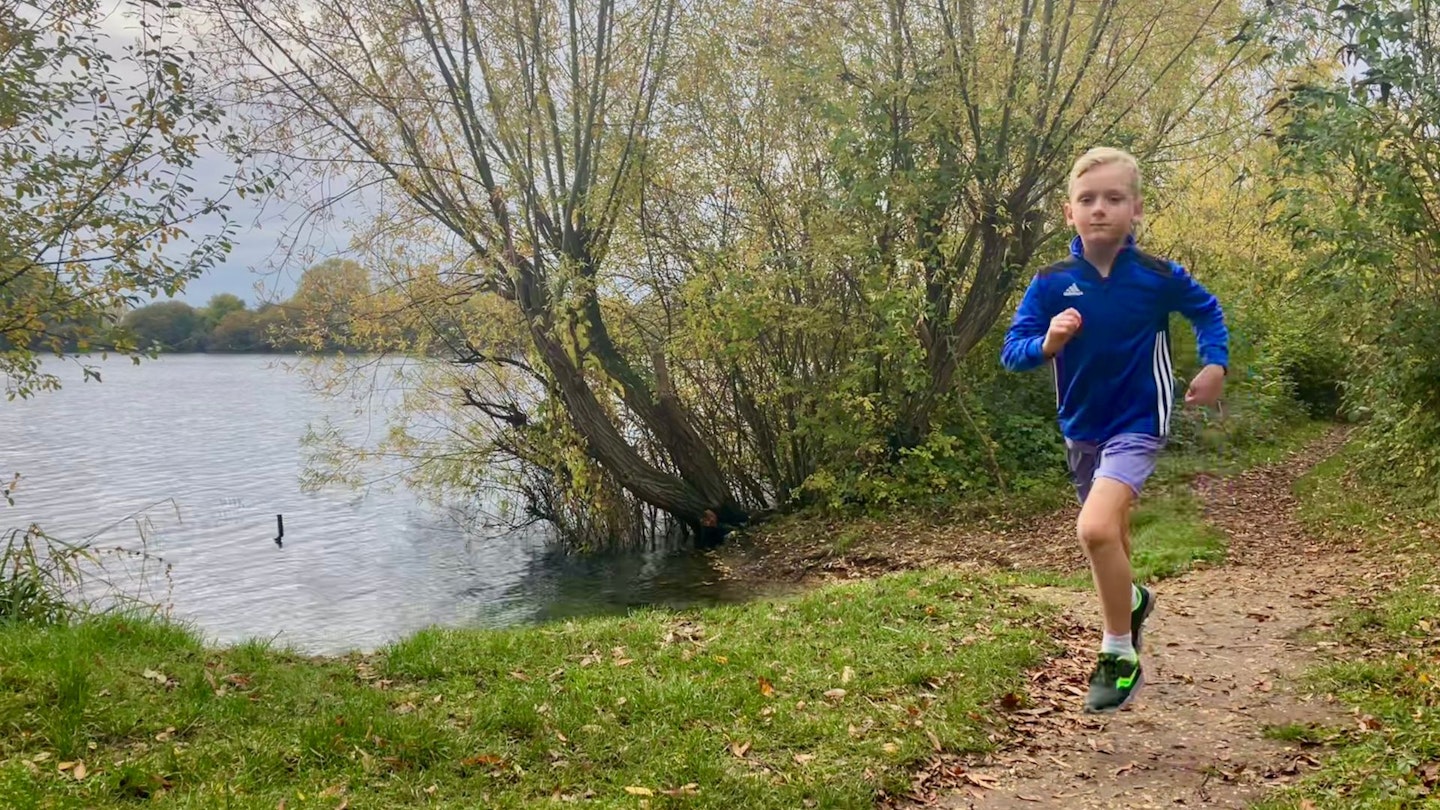 kid running next to lake