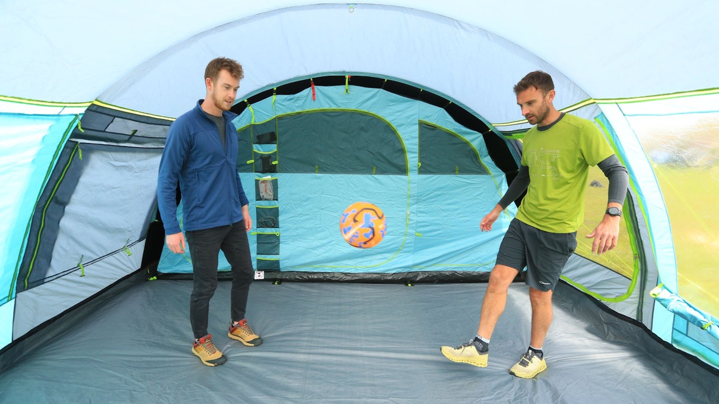 Two people playing football inside Coleman Meadowood 6L BlackOut Tent