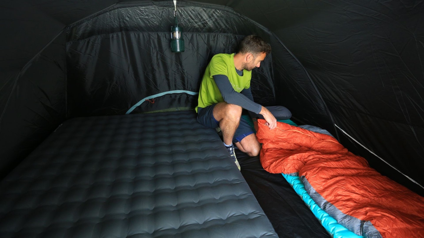 Decathlon Quechua Arpenaz 4.1 F&B bedroom with double and single airbeds and person adding a sleeping bag