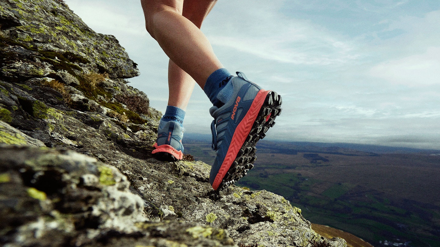 Close up of INOV8 ROCLITE boots being worn on an ascent of a rocky ridge
