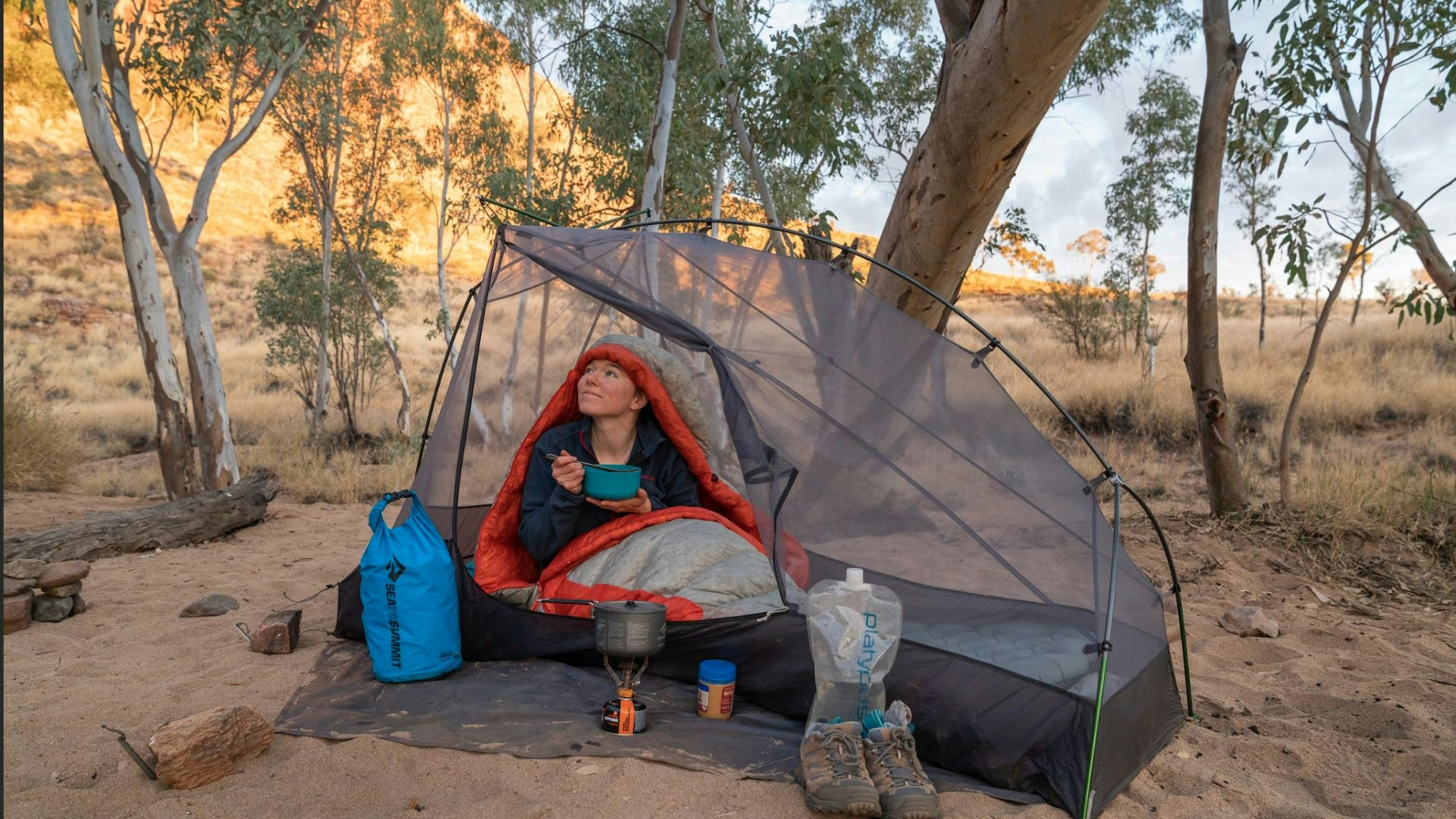 Woman eats breakfast in a tent in the outback.