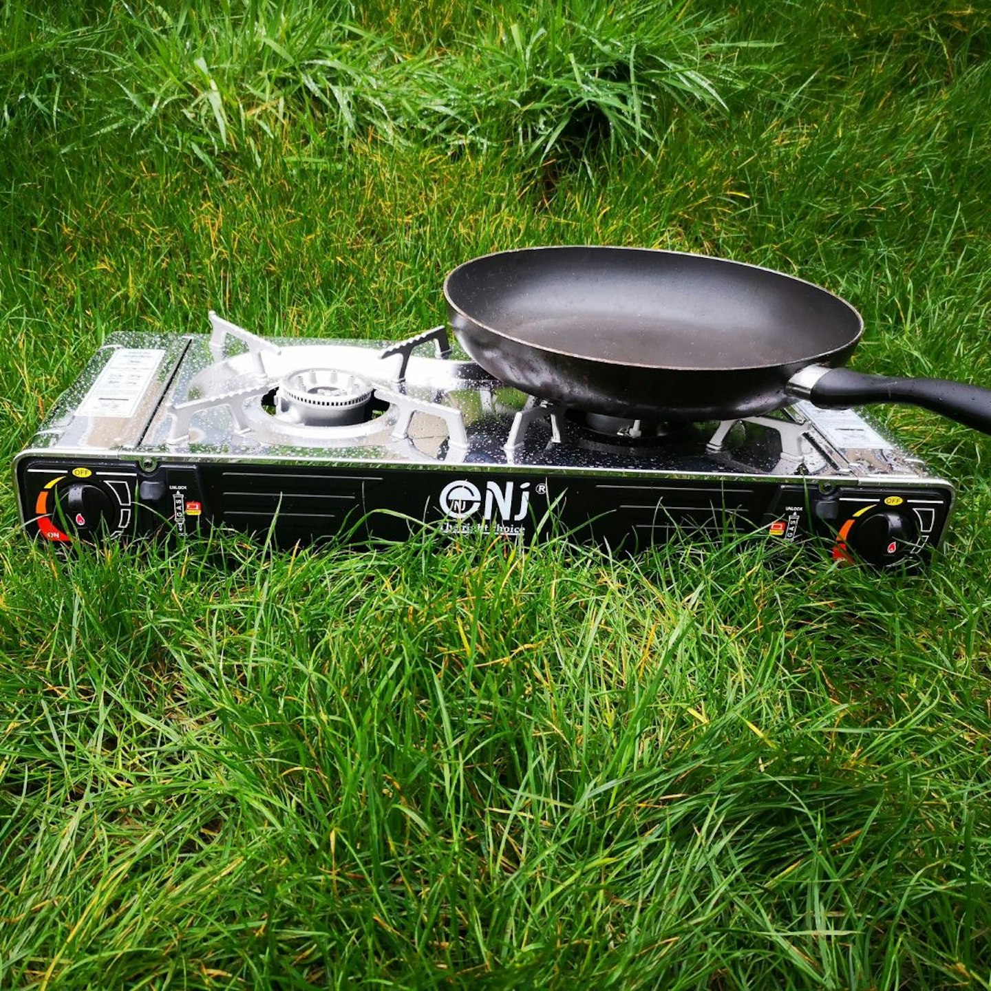 NK stove in long grass with pan