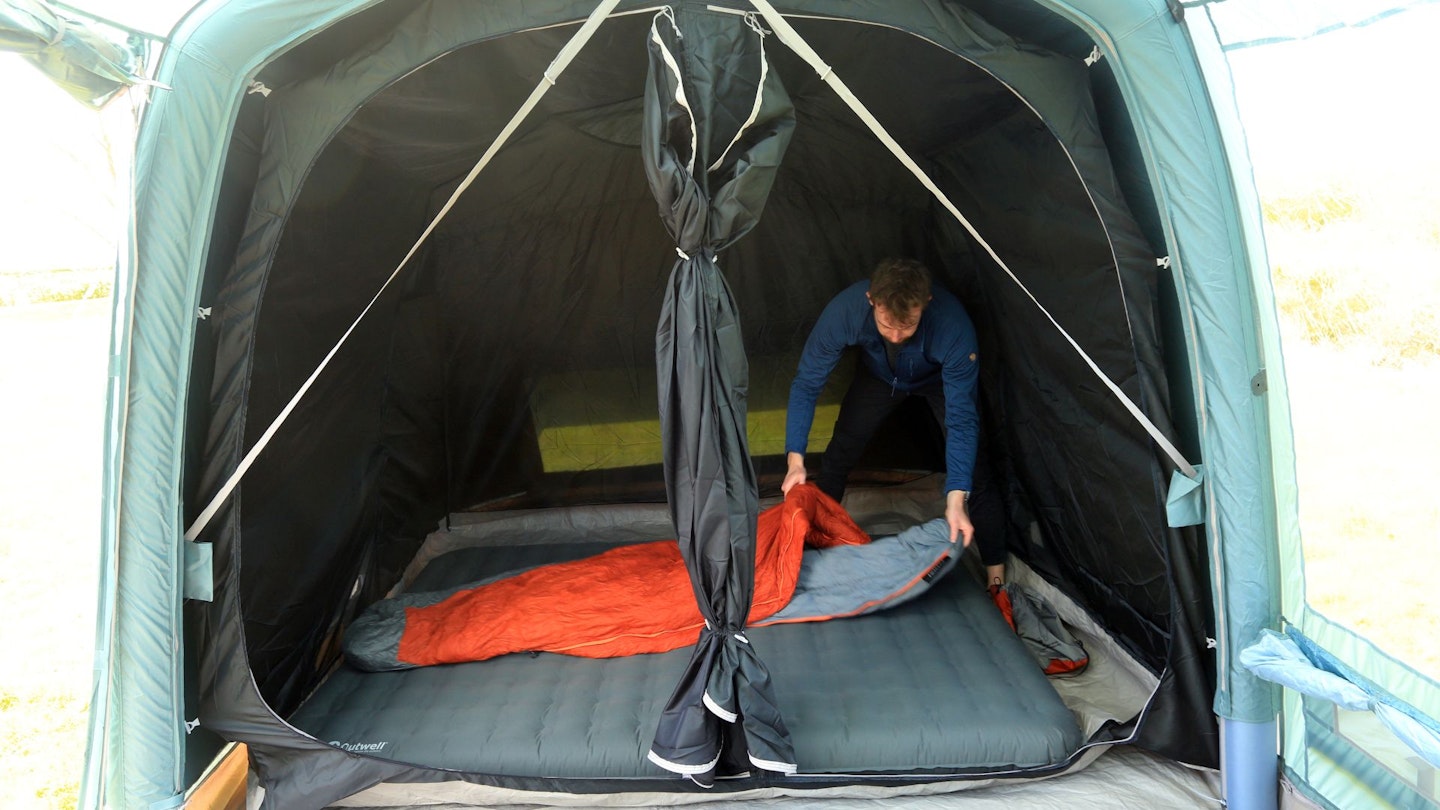 Person putting sleeping gear inside Vango Castlewood Air 800XL Package bedroom