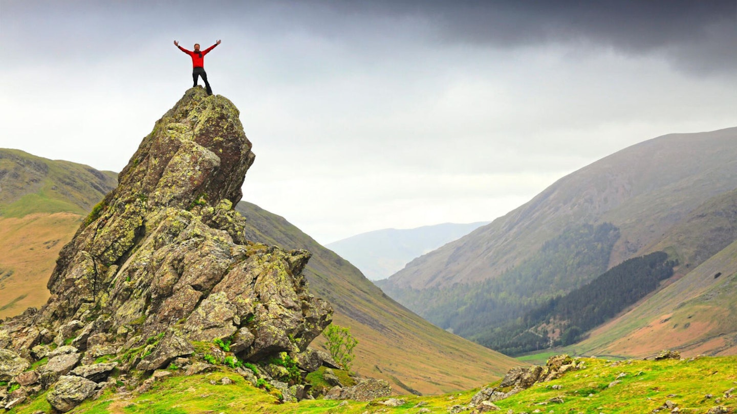 Walker on top of Helm Crag summit Howitzer Lake District