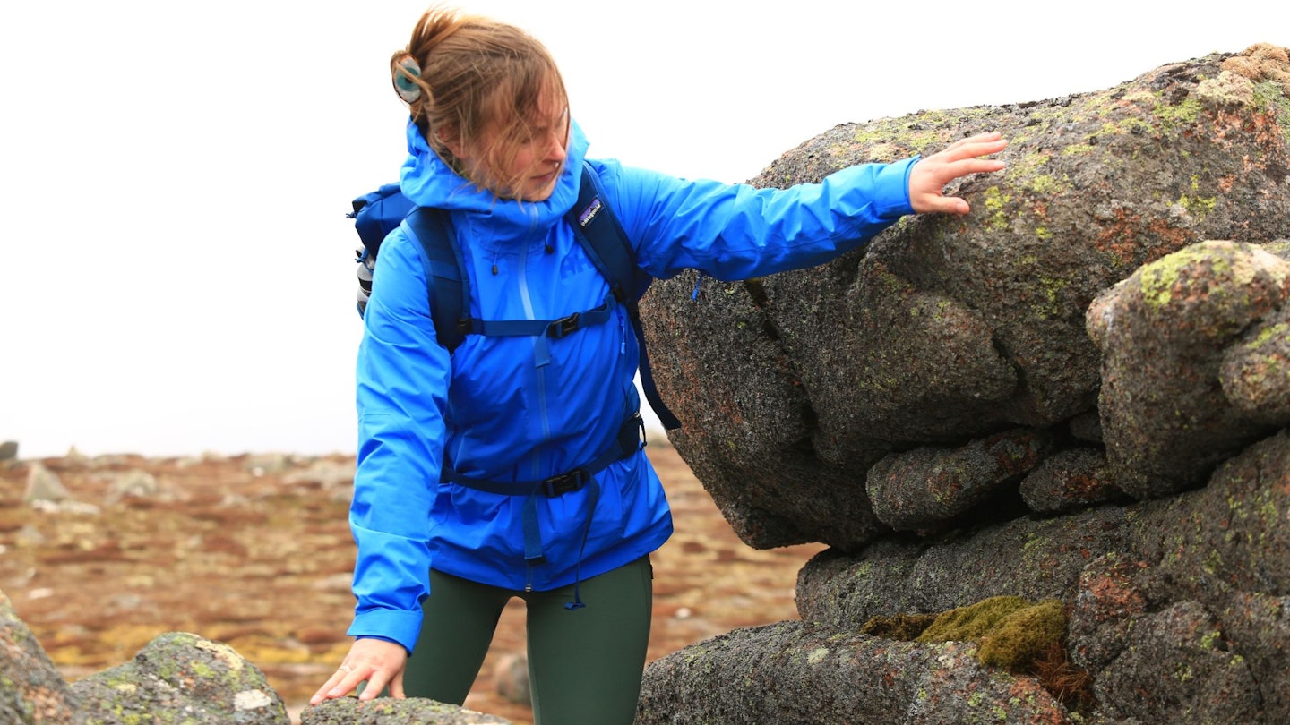Hiker scrambling up a mountain wearing Helly Hansen Verglas Infinity Shell Jacket