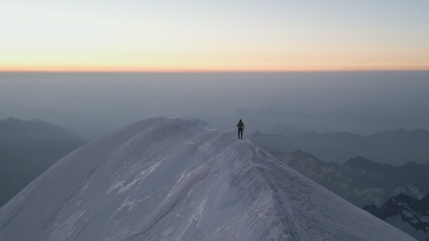 Alex Steindl in the distance running on snowy paths on alpine peaks of the Spaghetti tour