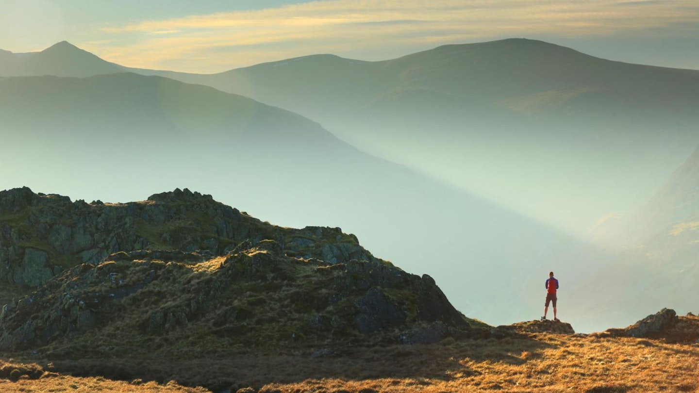 Hiker on Place Fell, looking to Helvellyn range Lake District